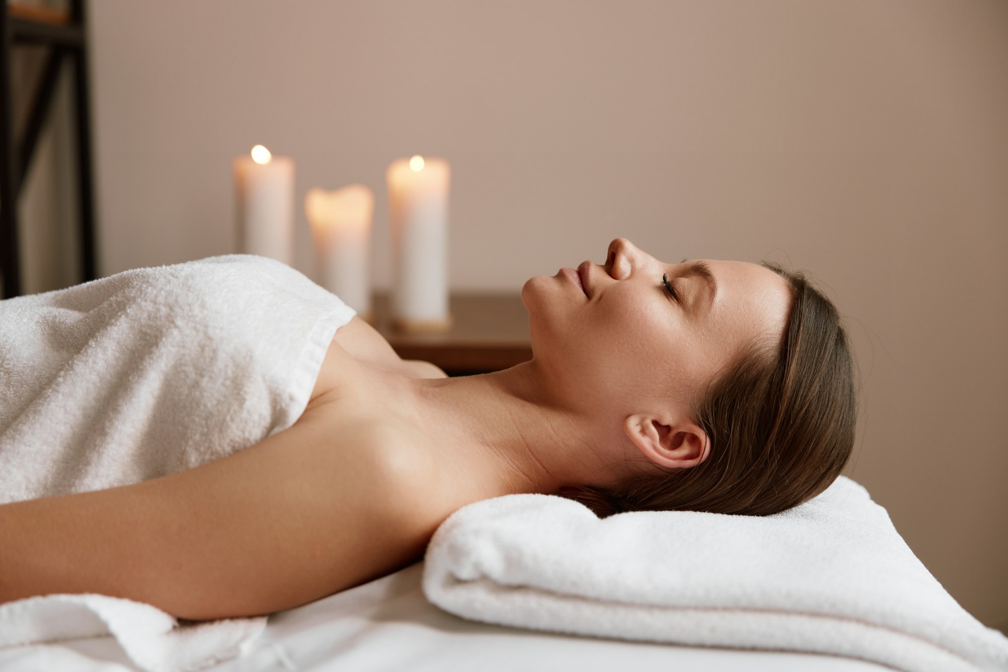 Side view of peaceful woman relaxing in spa salon after massage